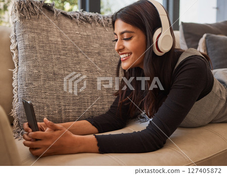 Relax, headphones and woman with phone, sofa and home living room streaming online music, podcast or radio. Happy, smile and happy female enjoy listening to audio, playlist or favorite song in house Relax, headphones and woman with phone, sofa and home living room streaming online music, podcast or radio. Happy, smile and happy female enjoy listening to audio, playlist or favorite song in house 127405872