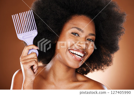 Happy black woman, hair care and comb in portrait with afro pick, beauty and self care by brown backdrop. African woman, model and cosmetics with makeup or happiness for combing by studio background 127405990