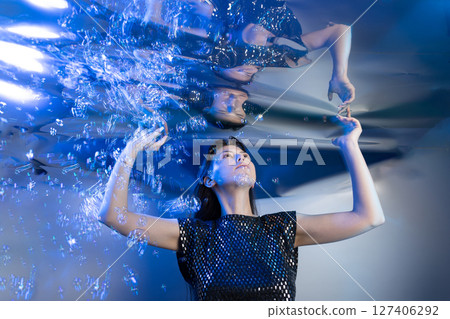 Girl in a Stunning Mermaid Outfit Submerged in Shimmering Water Creating an Enchanting Atmosphere 127406292