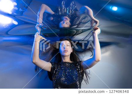 Girl With Long Hair Resembling a Mermaid Under Shimmering Blue Lights Girl With Long Hair Resembling a Mermaid Under Shimmering Blue Lights 127406348