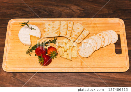 Appetizer different types of cheeses on cutting board with fresh strawberries on wooden table. Appetizer different types of cheeses on cutting board with fresh strawberries on wooden table. 127406513