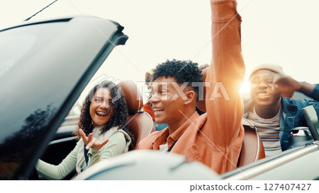 Celebration, drive and road trip with happy friends in car together for holiday, travel or vacation. Arm raised, energy and success with group of people riding in convertible vehicle for getaway 127407427