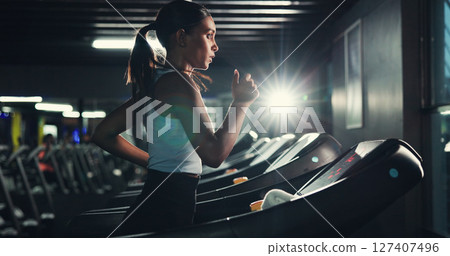 Exercise, girl and running on treadmill in gym at night for agility training, speed development or calorie burning. Flare, evening workout or woman on machine for cardio fitness or muscle performance 127407496