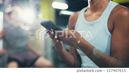 Hands, fitness and woman in gym, smartphone or message to contact, social media or training. Flare, mobile user or healthy person in wellness center, chatting or cellphone with exercise or progress 127407615