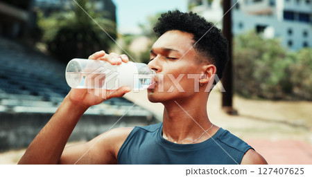 Stadium, man and fitness with drinking water for wellness, hydration and nutrition on workout break. Outdoor, male person and athlete with bottle for h2o liquid, detox and beverage after exercise 127407625