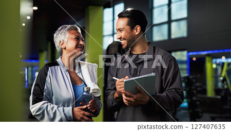 Man, woman and talking with tablet at gym for advice, sign up and smile for exercise tips. Mature person, personal trainer and touchscreen with training app, workout and discussion at fitness center Man, woman and talking with tablet at gym for advice, sign up and smile for exercise tips. Mature person, personal trainer and touchscreen with training app, workout and discussion at fitness center 127407635