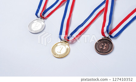 Gold silver and bronze demonstration trophy medals with ribbon for school university or national or olympic sport even organization competition. Isolated on white background. Award and victory concept 127410352