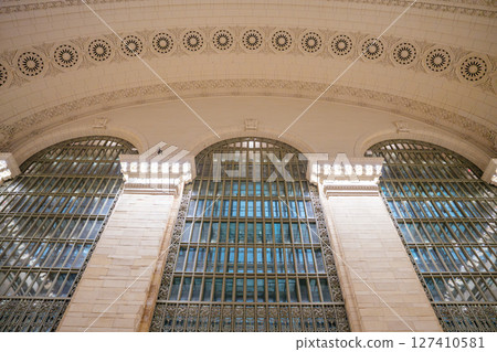 A detailed view of the tall arched windows and ornate ceiling architecture inside Grand Central Terminal. The classic Beaux-Arts design features intricate carvings and elegant lighting. 127410581