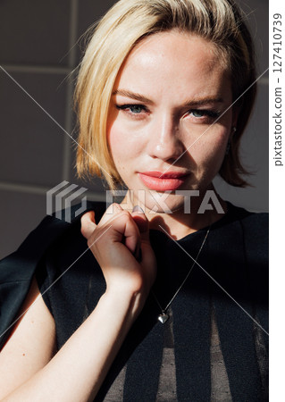 beautiful fashionable slender blonde woman in a black evening summer dress sitting on a chair beautiful fashionable slender blonde woman in a black evening summer dress sitting on a chair 127410739