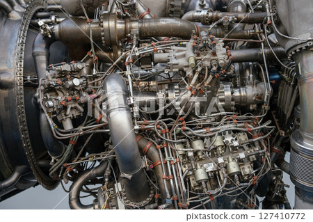 Extreme close-up view of the rocket engine showing intricate wiring, pipes, and control modules. The image highlights the complex engineering of a spacecraft propulsion system. Extreme close-up view of the rocket engine showing intricate wiring, pipes, and control modules. The image highlights the complex engineering of a spacecraft propulsion system. 127410772