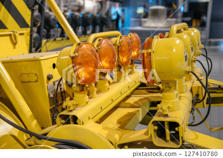 The image shows a detailed view of multiple amber-colored rotating warning lights mounted on a yellow utility trailer. These lights are typically used for safety or signaling in industrial and The image shows a detailed view of multiple amber-colored rotating warning lights mounted on a yellow utility trailer. These lights are typically used for safety or signaling in industrial and 127410780