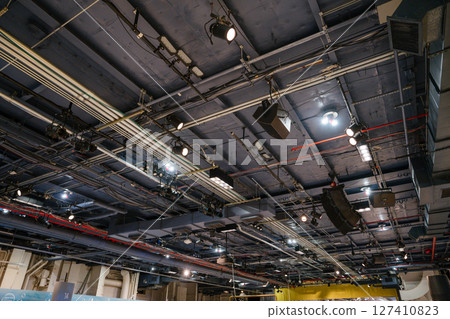 Detailed view of the ceiling inside the Intrepid Museum showing lighting equipment, pipes, and speakers. The exposed industrial infrastructure supports sound and light systems for exhibits and Detailed view of the ceiling inside the Intrepid Museum showing lighting equipment, pipes, and speakers. The exposed industrial infrastructure supports sound and light systems for exhibits and 127410823