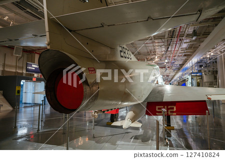 A museum exhibit featuring the tail section of a military jet aircraft. The engine exhaust is covered, and Beware of Blast is marked near the nozzle. 127410824