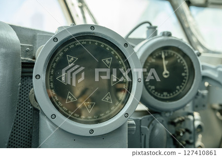 A detailed close-up of an old ship's compass alongside a speed gauge measured. These vintage navigation instruments are mounted inside a maritime control panel on a ship's bridge. A detailed close-up of an old ship's compass alongside a speed gauge measured. These vintage navigation instruments are mounted inside a maritime control panel on a ship's bridge. 127410861