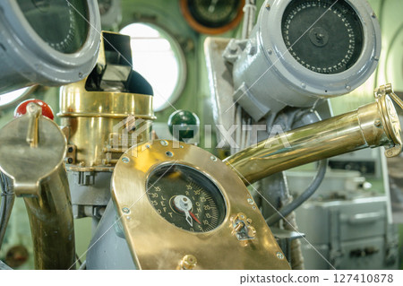 Close-up of antique ship steering equipment, including a polished brass compass and navigation dials. The instruments are housed inside a historical vessel's control room. 127410878