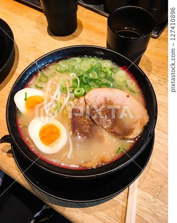 a vertical photo of cloase up of a bowl of Japanese soup ramen (pork slice, boiled egg, spring onion) with wooden chopsticks on the side a vertical photo of cloase up of a bowl of Japanese soup ramen (pork slice, boiled egg, spring onion) with wooden chopsticks on the side 127410896