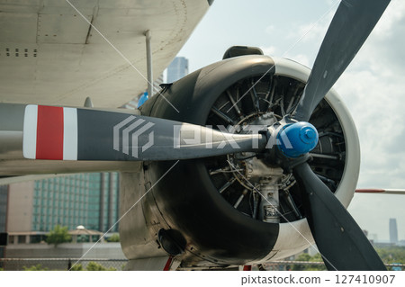 Detailed view of a vintage military aircraft's propeller engine with exposed mechanical components. The large black blades and radial engine are seen from below the wing. 127410907