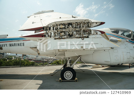 Close-up of the open wing mechanism and landing gear of a white Navy Marines jet. The aircraft is on display outdoors with mechanical systems visible under the wing. Close-up of the open wing mechanism and landing gear of a white Navy Marines jet. The aircraft is on display outdoors with mechanical systems visible under the wing. 127410969