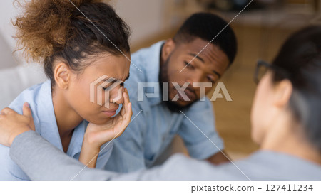 Counselor Comforting Upset African American Wife Crying Next To Husband At Couples Therapy. Selective Focus 127411234