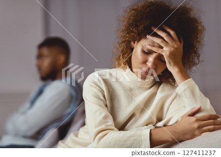 Relationship problems. Black man and woman avoiding talking, sitting on different sides of couch 127411237