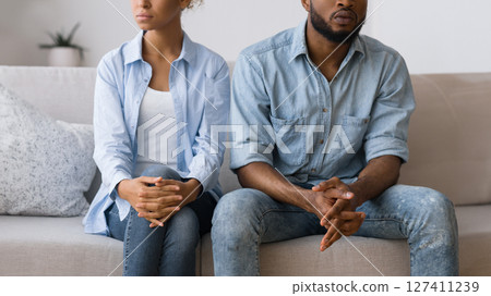 Misunderstanding Between Spouses. Afro Couple Avoiding Eye Contact After Quarrel Sitting On Couch At Counselor's Office, Cropped Misunderstanding Between Spouses. Afro Couple Avoiding Eye Contact After Quarrel Sitting On Couch At Counselor's Office, Cropped 127411239