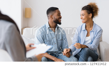 Gladful African American Couple Smiling And Laughing On Sofa After Effective Marital Therapy. Selective Focus 127411412