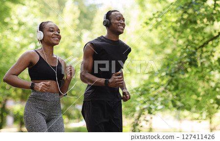 Jogging Couple. Happy Black Guy And Girl Running In Morning Park Together, Feeling Healthy And Motivated, Copy Space Jogging Couple. Happy Black Guy And Girl Running In Morning Park Together, Feeling Healthy And Motivated, Copy Space 127411426