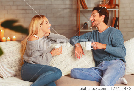 Happy Couple Enjoying Conversation Having Coffee Sitting On Couch At Home. Selective Focus 127411480