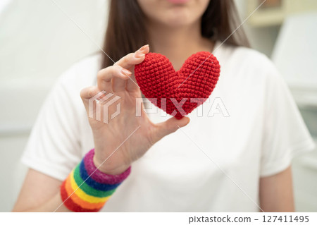 Asian LGBT woman holding heart rainbow flag. Asian LGBT woman holding heart rainbow flag. 127411495