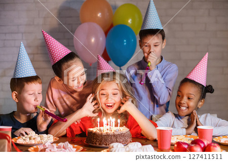 Kids looking at birthday cake with candles, having b-day party Kids looking at birthday cake with candles, having b-day party 127411511