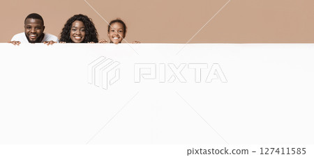 Offer for families. African american parents and little daughter leaning on blank white advertisement board with free space 127411585