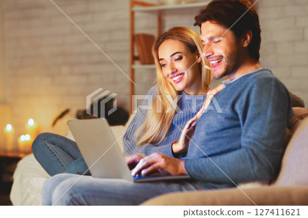 Happy Spouses Browsing On Laptop Sitting Together Relaxing On Sofa At Home. Selective Focus 127411621