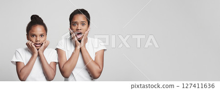Shocked emotional black girls touching cheeks on grey background Shocked emotional black girls touching cheeks on grey background 127411636