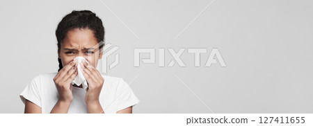 Sickness, illness, virus concept. Teen black girl blowing nose over grey studio background Sickness, illness, virus concept. Teen black girl blowing nose over grey studio background 127411655