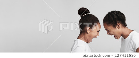 Generation conflict. Furious black sisters quarreling, grey studio background Generation conflict. Furious black sisters quarreling, grey studio background 127411656