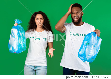 Stop Using Plastic. Two Displeased Multicultural Volunteers Shouting Holding Blue Garbage Bags Full Of Litter Standing On Green Studio Background. Sort Your Waste And Don't Litter Concept Stop Using Plastic. Two Displeased Multicultural Volunteers Shouting Holding Blue Garbage Bags Full Of Litter Standing On Green Studio Background. Sort Your Waste And Don't Litter Concept 127411677
