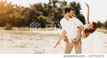 After-Quarantine Summer. Parents And Daughter Walking Having Fun Together Outside On Sunny Day After Quarantine. Father Carrying Child And Laughing. 127412251