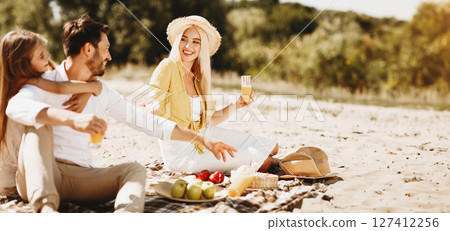 Young family enjoying picnic together, resting in nature and drinking juice 127412256