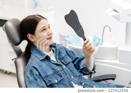 Young patient admiring her smile after dental checkup 127412338