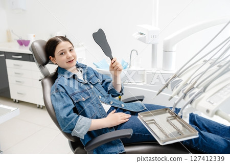 Young patient admiring her smile after dental checkup 127412339