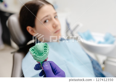 Dentist showing dental mold to young patient in clinic Dentist showing dental mold to young patient in clinic 127412350
