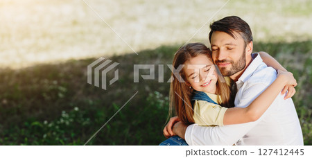 Daughter's love. Little girl hugging her father, having picnic in park 127412445