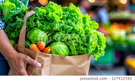 A person holding a paper bag full of fresh vegetables A person holding a paper bag full of fresh vegetables 127412593