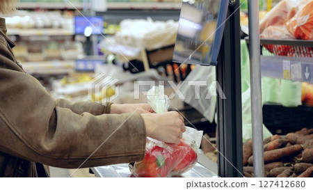 Customer using electronic scales to weigh fresh produce in grocery store and choose healthy ingredients for meal prep Customer using electronic scales to weigh fresh produce in grocery store and choose healthy ingredients for meal prep 127412680