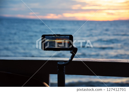 Smartphone mounted on gimbal captures sunset over ocean Smartphone mounted on gimbal captures sunset over ocean 127412701