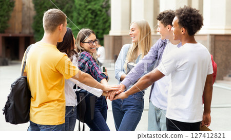 Togetherness, unity concept. Students putting their hands together in college campus 127412821