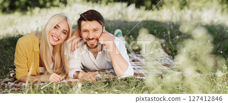 Summer Romance. Lovely Couple Having Picnic Date Lying On Plaid On Green Grass In Park After Reopening, Smiling To Camera. 127412846