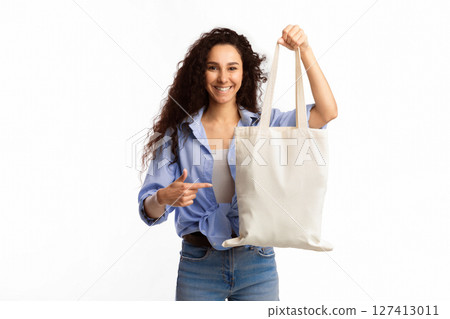 Use Eco Bag. Smiling Woman Pointing Finger At White Textile Shopper Handbag Standing Over White Studio Background. Eco-Friendly Lifestyle, Fashion And Ecology, Stop Using Plastic Concept 127413011