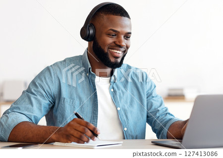 Online Education. Smiling Black Guy In Headphones Study With Laptop And Taking Notes, Cheerful Millennial African American Man Using Computer And Writing Down Information, Enjoying Distance Learning Online Education. Smiling Black Guy In Headphones Study With Laptop And Taking Notes, Cheerful Millennial African American Man Using Computer And Writing Down Information, Enjoying Distance Learning 127413086