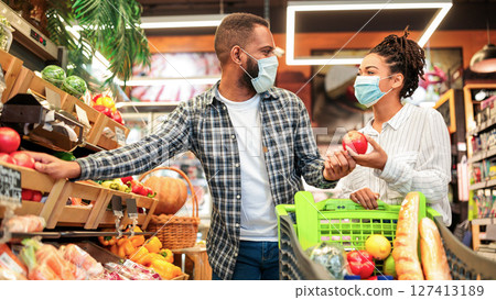 Grocery Shopping. African Family Couple In Masks Buying Vegetables Together Standing With Shop Cart In Supermarket Groceries Store Indoor. Buyers Choosing Healthy Food Concept 127413189